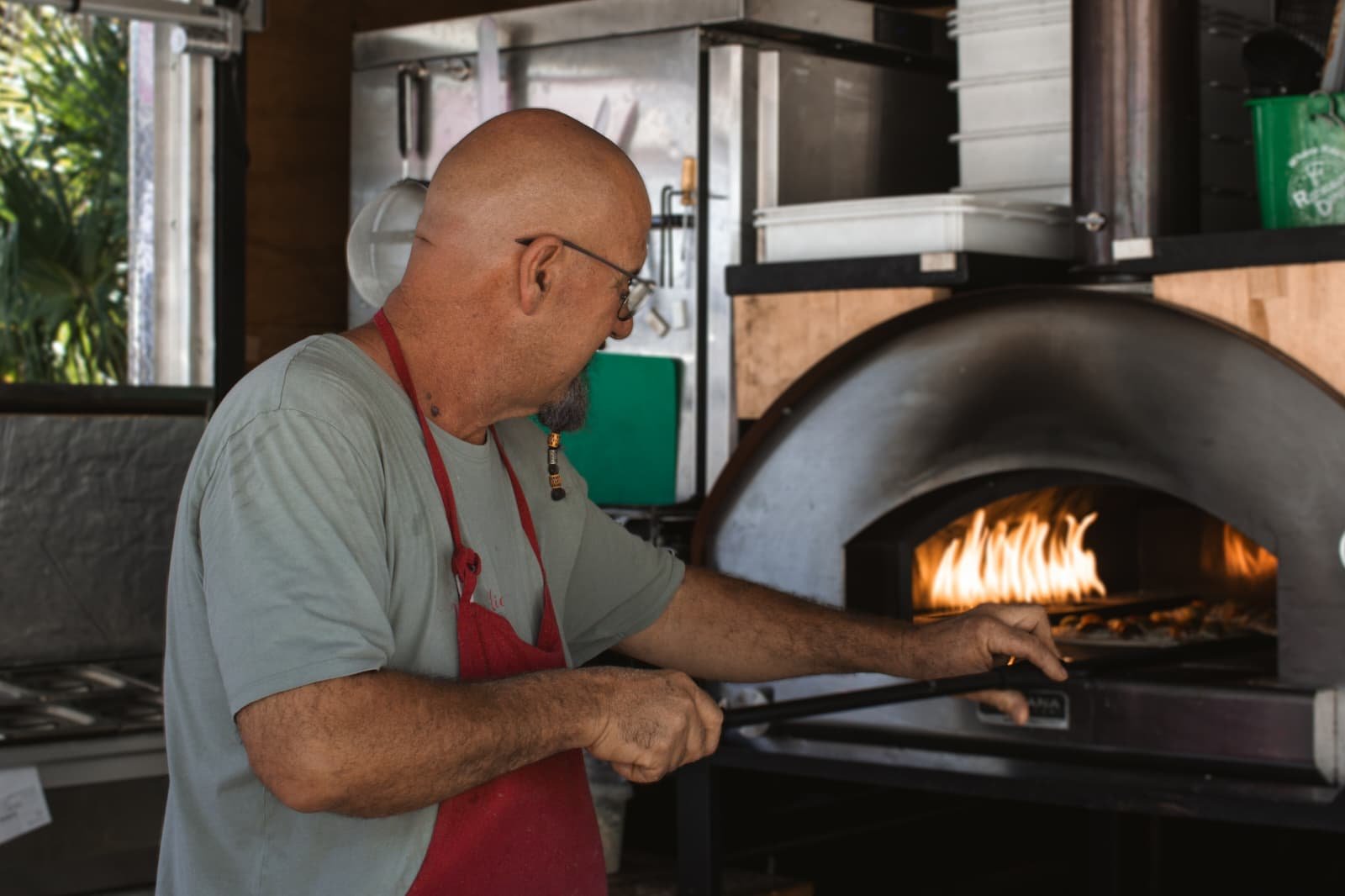 Un pizzaiolo enfourne une pizza dans un four à bois traditionnel
